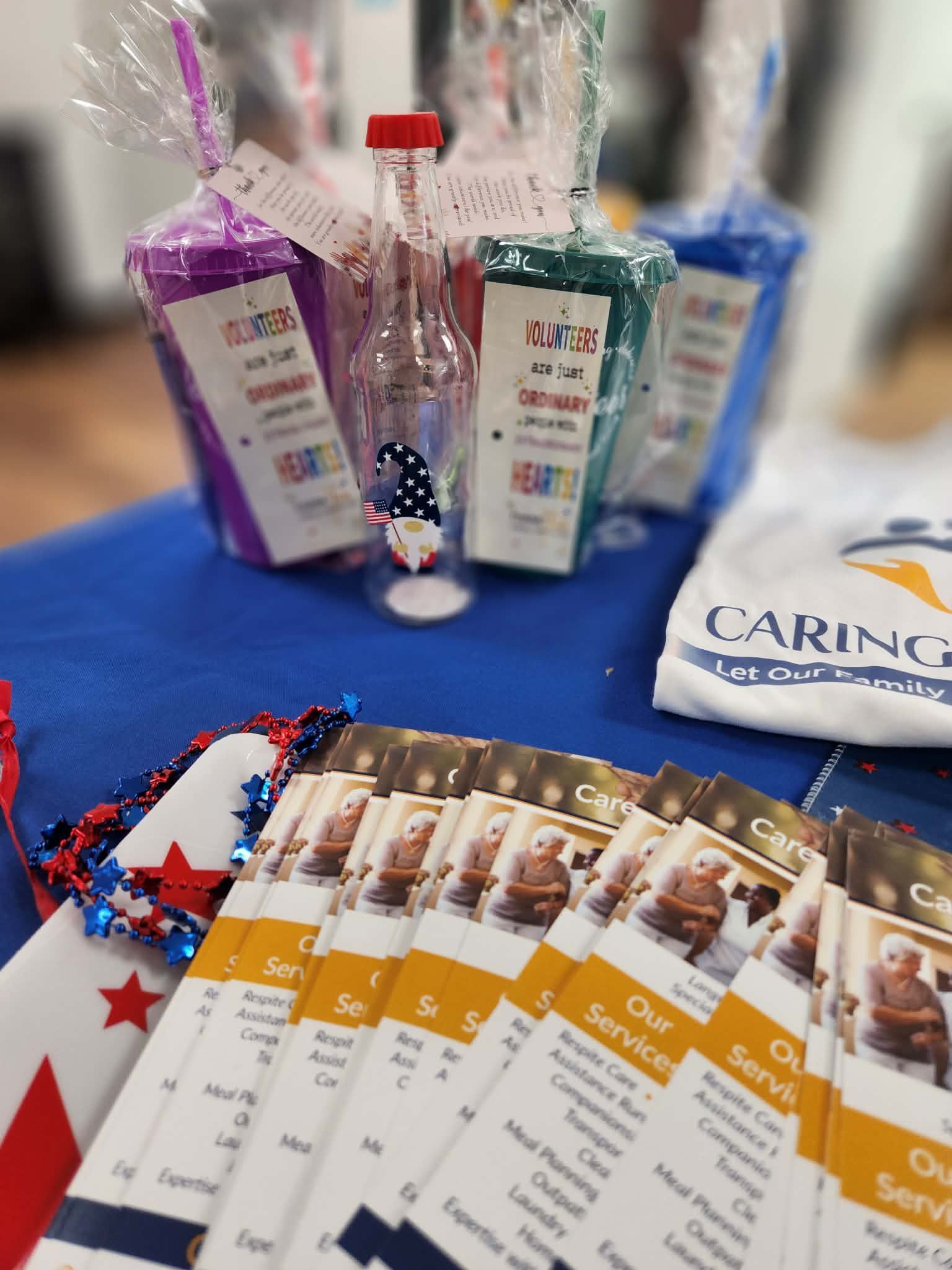 Care package items on a blue table: soap, sanitizer, tissues, and brochures in clear gift bags.