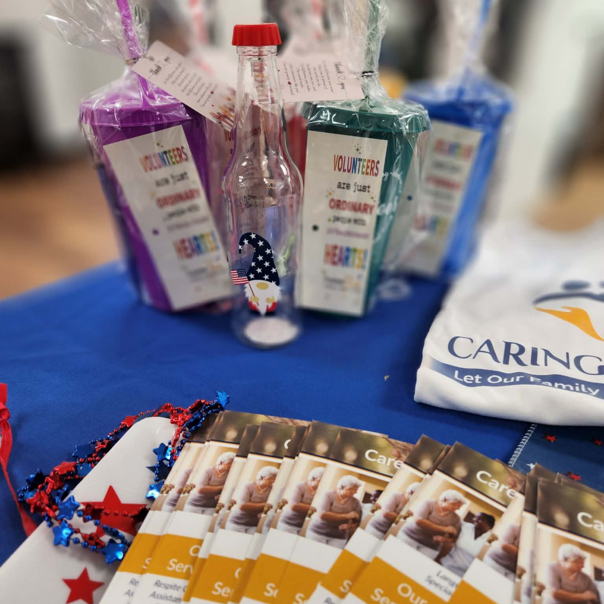 Care package items on a blue table: soap, sanitizer, tissues, and brochures in clear gift bags.