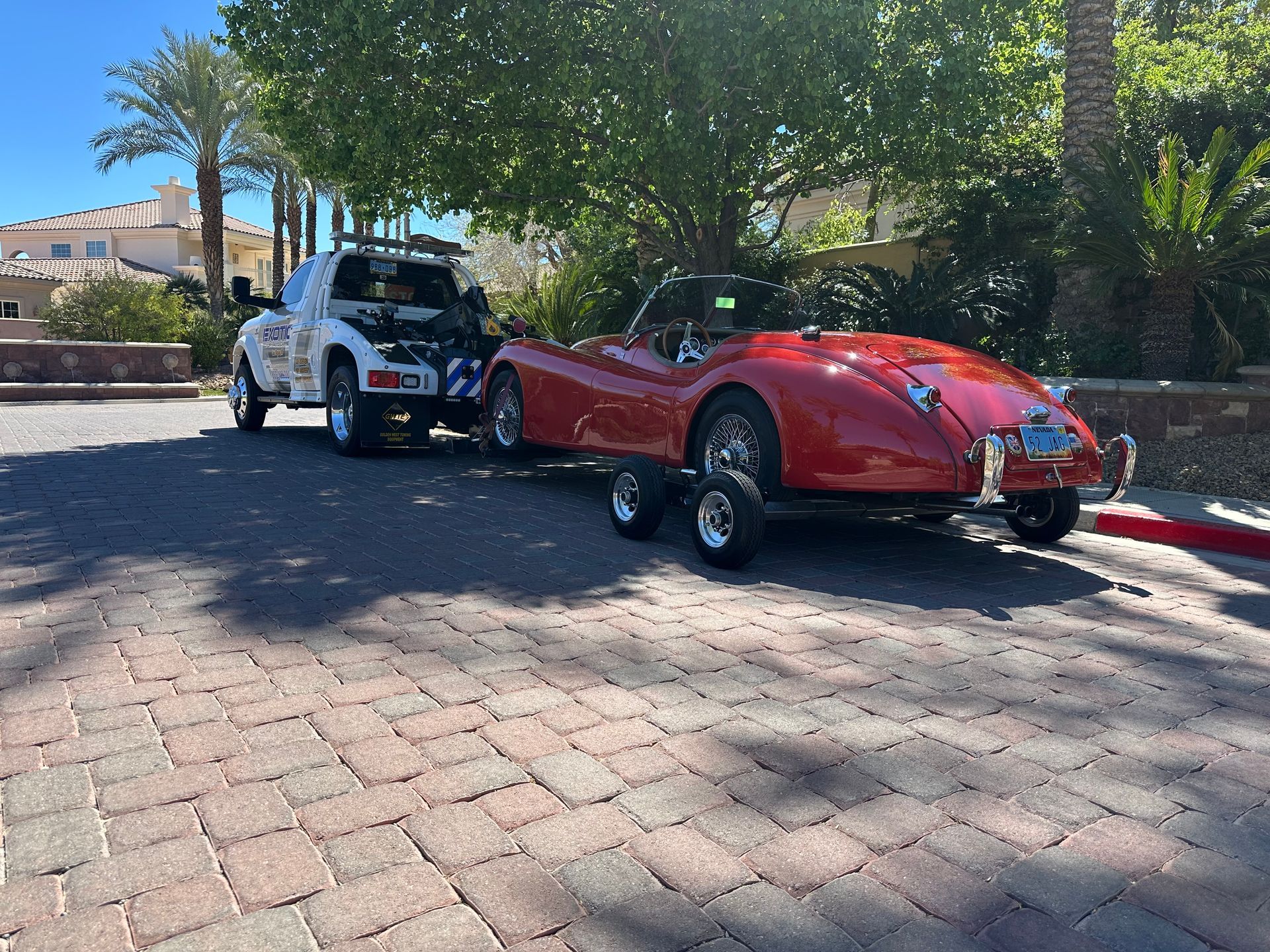 White tow truck with red car behind it on trailer
