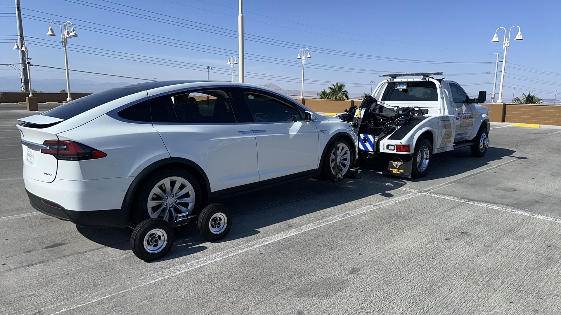 white car on trainer behind tow truck