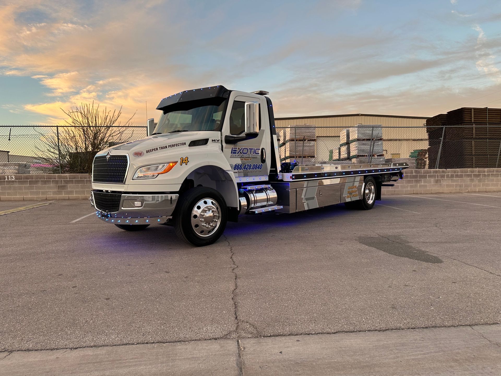 White tow truck on a paved lot at sunset with a cargo of stacked blocks.