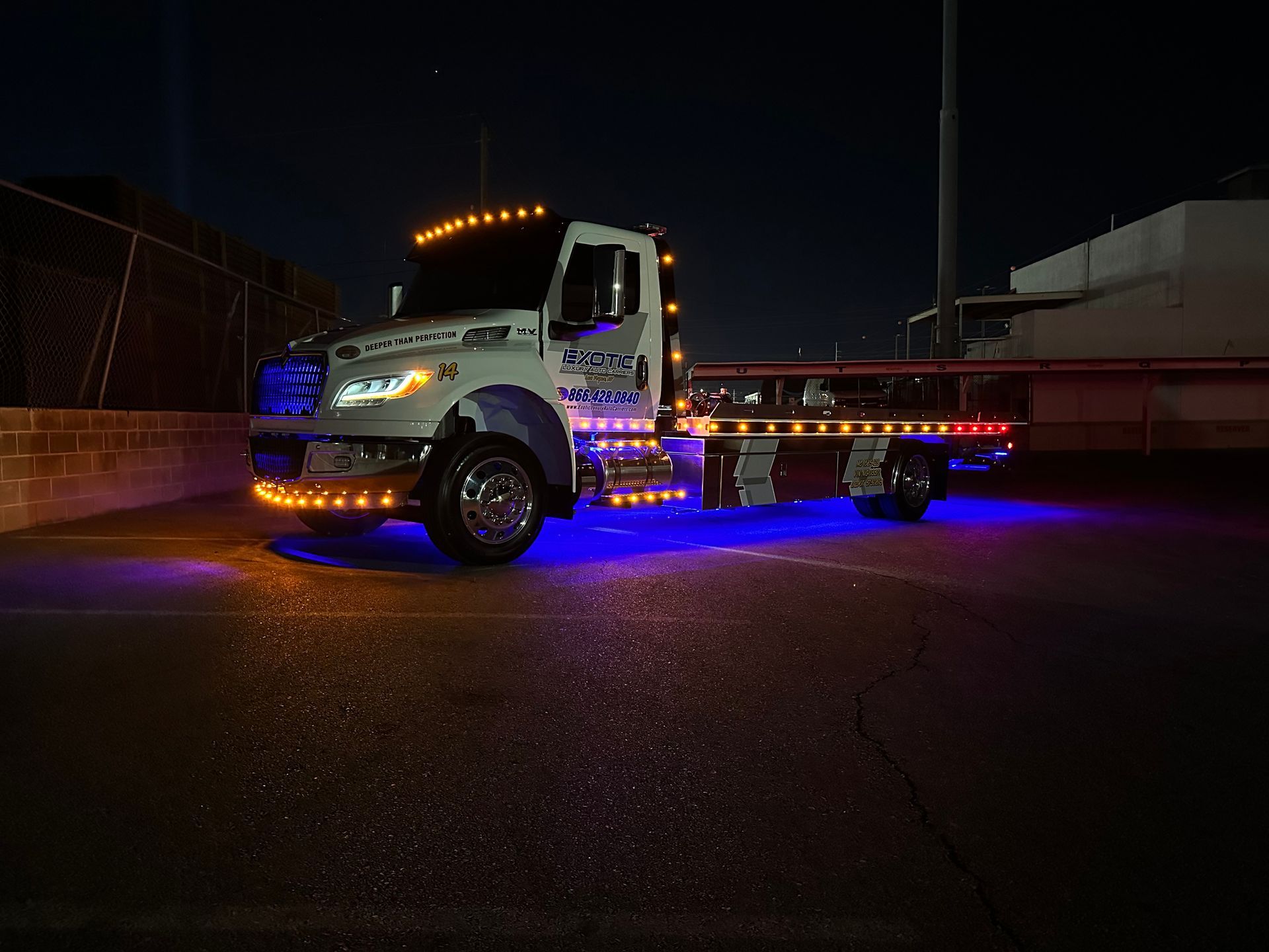 Tow truck lit with orange and blue lights at night.