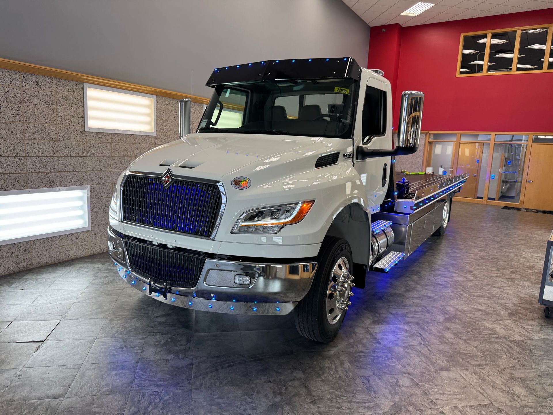 White tow truck in a showroom with blue underglow lighting.