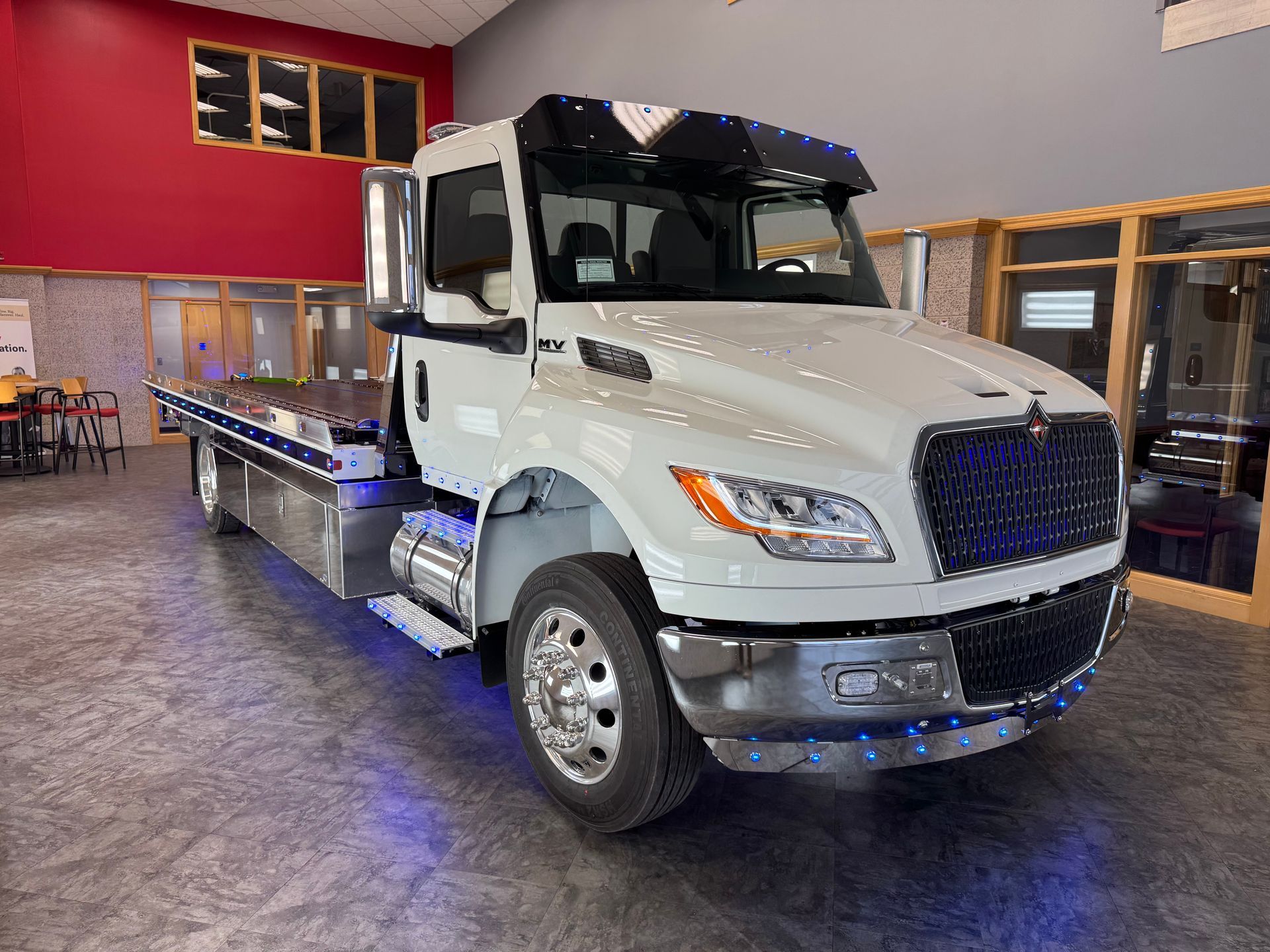 White tow truck in a showroom with a red and wood interior.