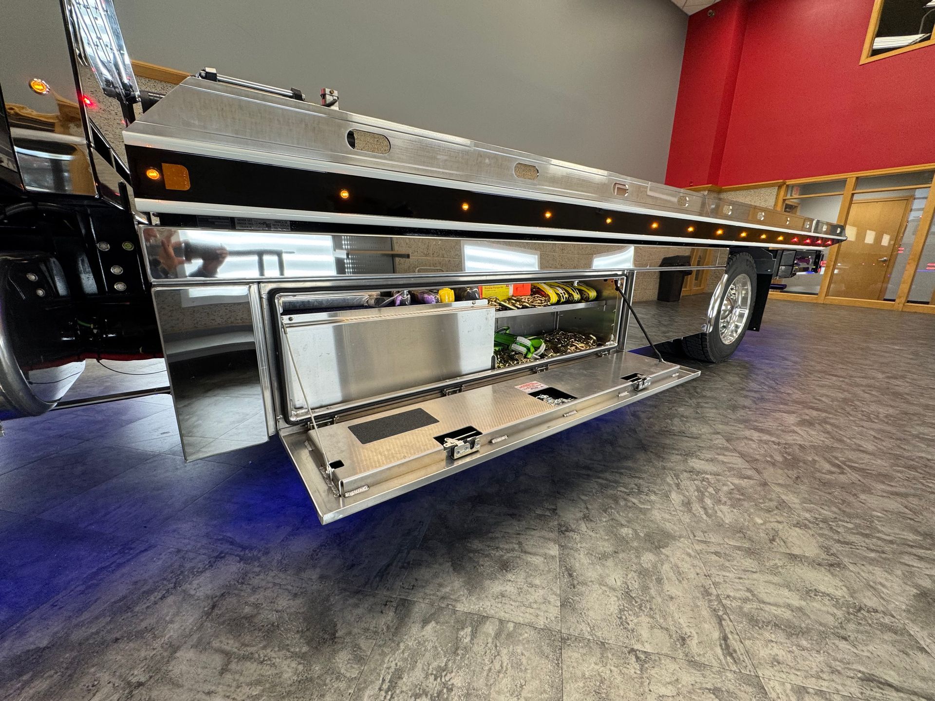 Tow truck with open storage compartment filled with equipment. Metallic finish, interior setting, blue underglow.