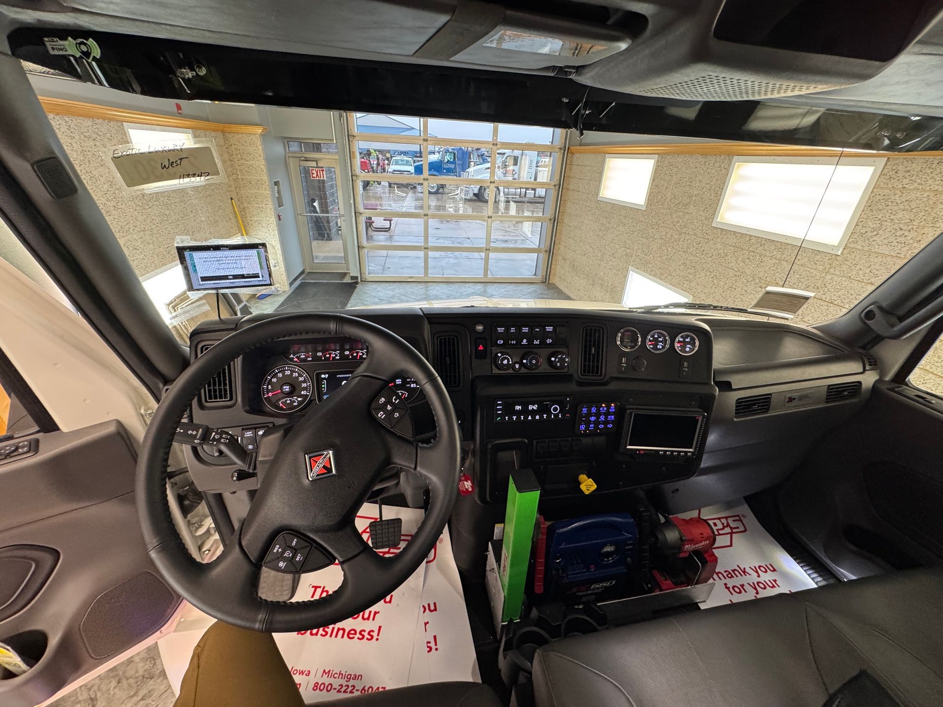 Interior view of a truck cab, showing the dashboard, steering wheel, and a view into a garage.