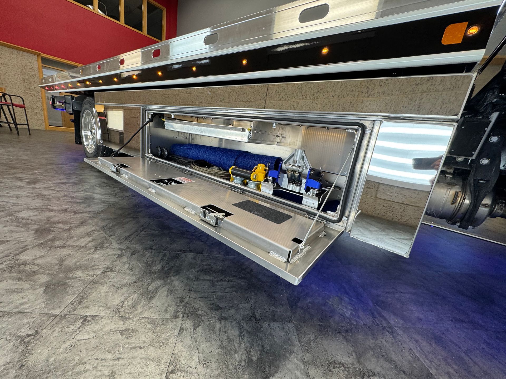 Open storage compartment on a truck trailer, revealing tools and equipment.