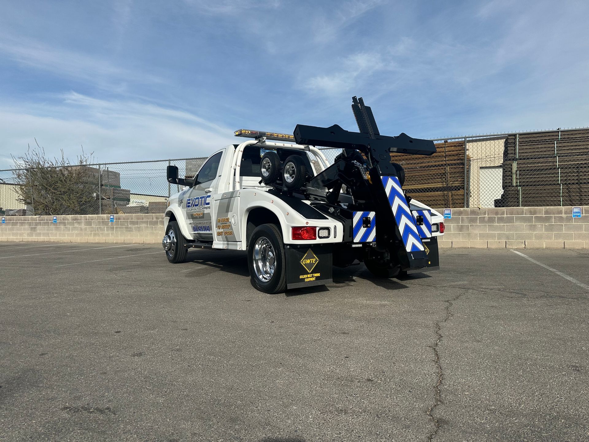 White tow truck with black and blue accents parked outside on a sunny day.