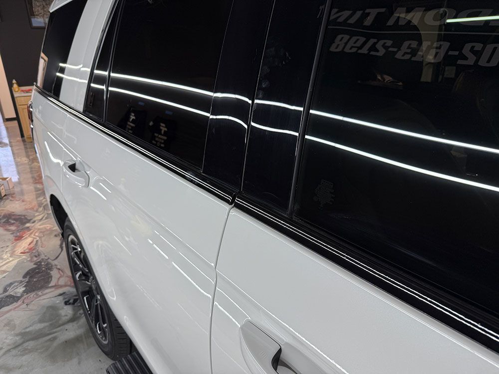 A white suv with black windows is parked in a garage.