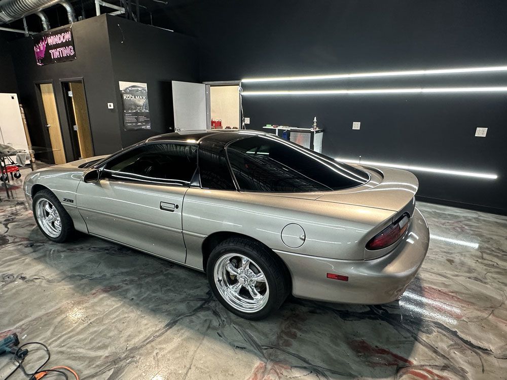 A silver chevrolet camaro is parked in a garage.
