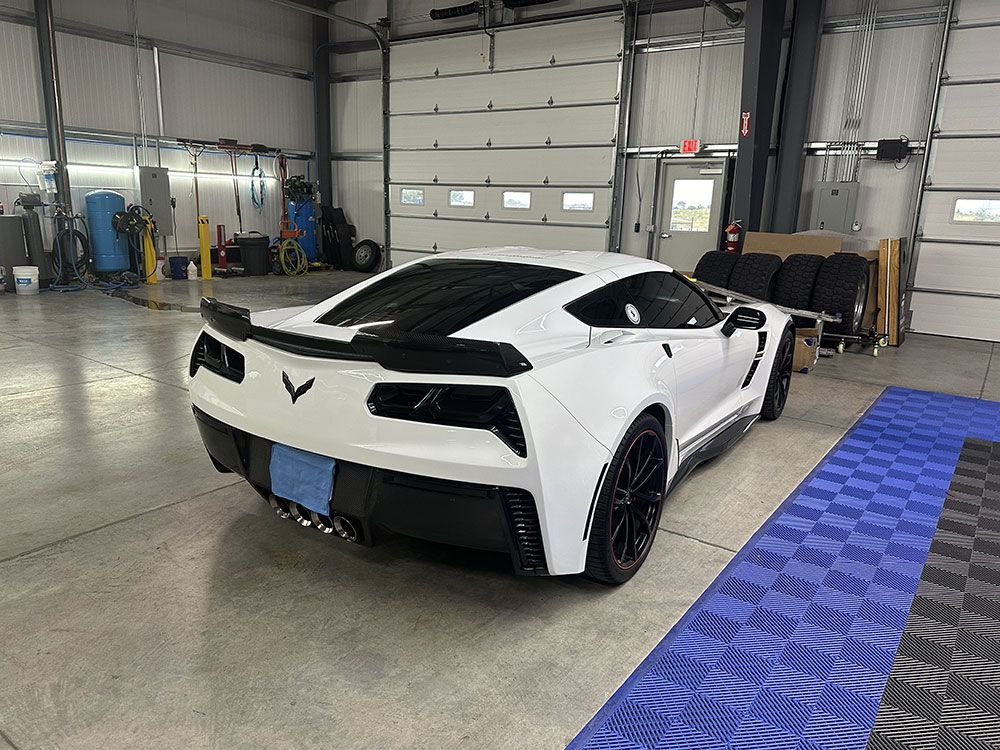A white corvette is parked in a garage.