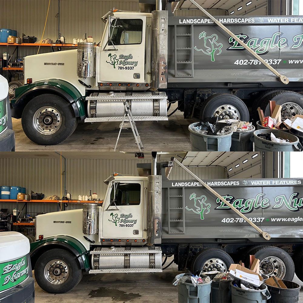 A dump truck is parked in a garage next to a trash can.