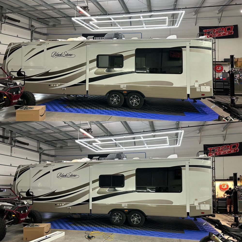 A rv is parked in a garage with a blue mat underneath it.