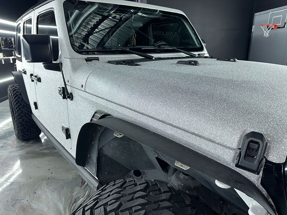 A white jeep wrangler is parked in a garage.