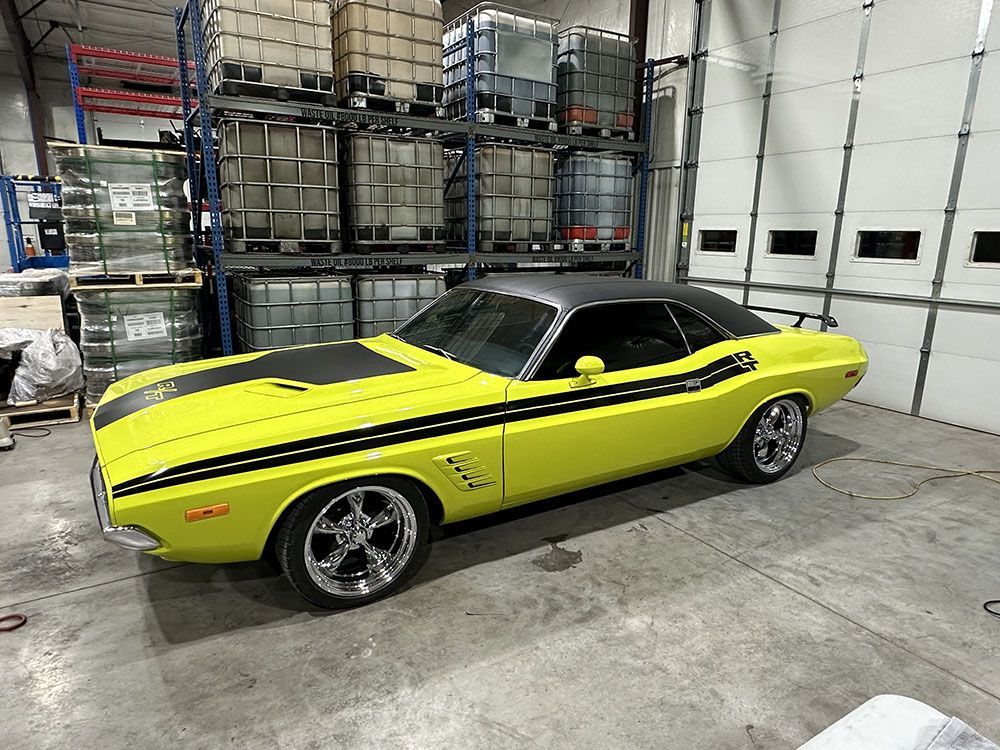 A yellow dodge challenger is parked in a garage.