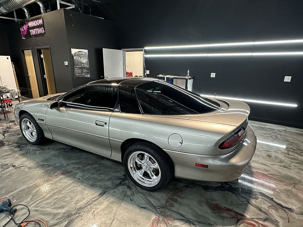 A silver chevrolet camaro is parked in a garage.