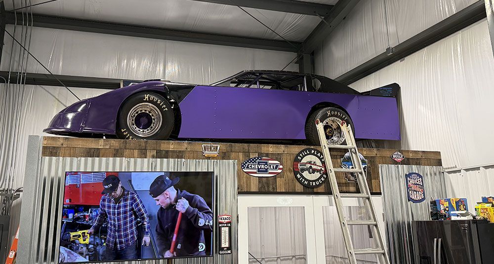 A purple race car is sitting on top of a wooden platform in a garage.