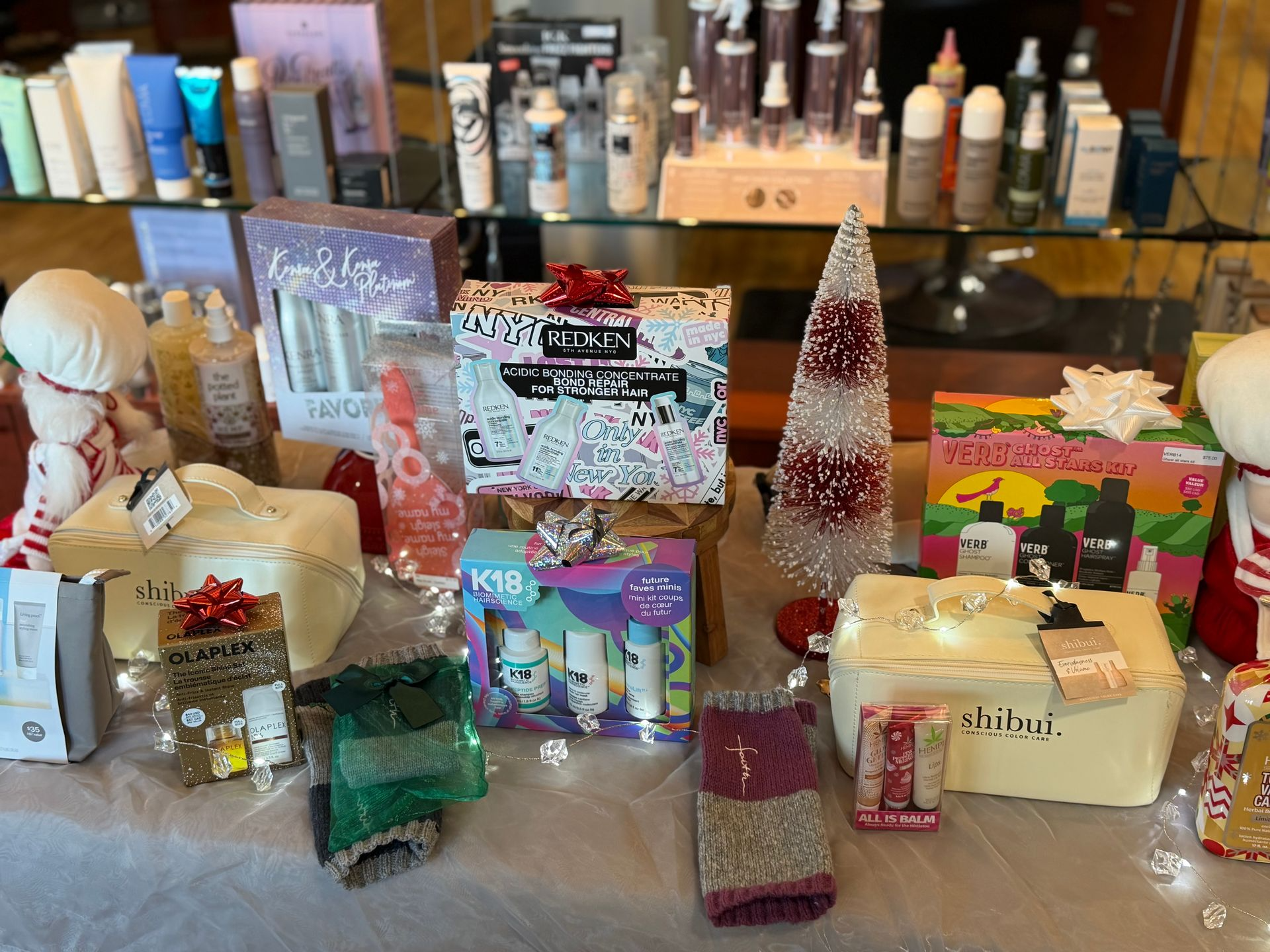Cosmetics and gifts displayed on a table with a small Christmas tree.