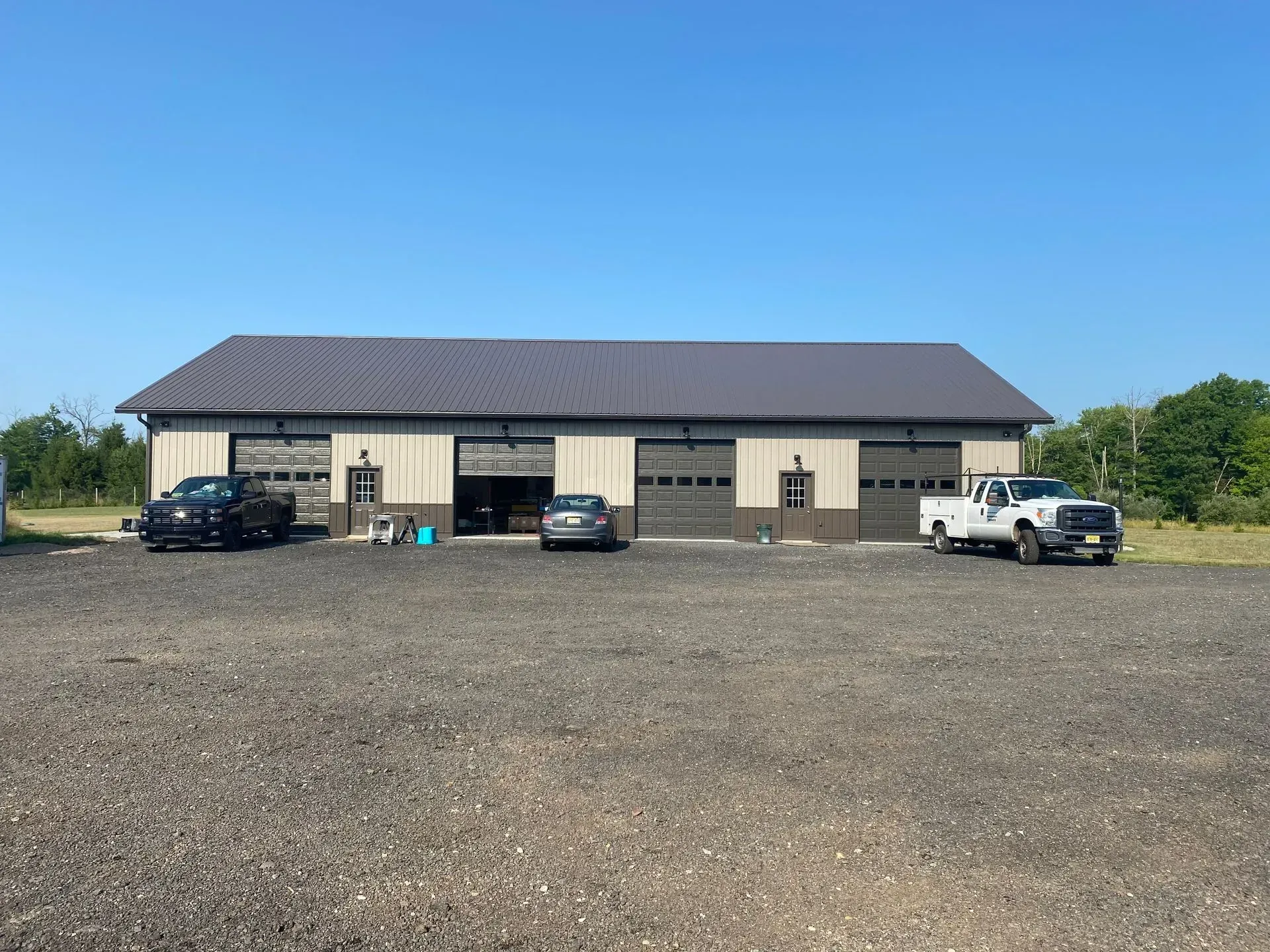 A single-story metal building with three garage bays; vehicles are parked in front.