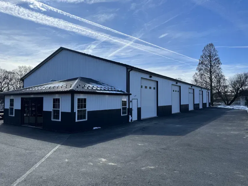 White and black industrial building with multiple garage doors on a sunny day.