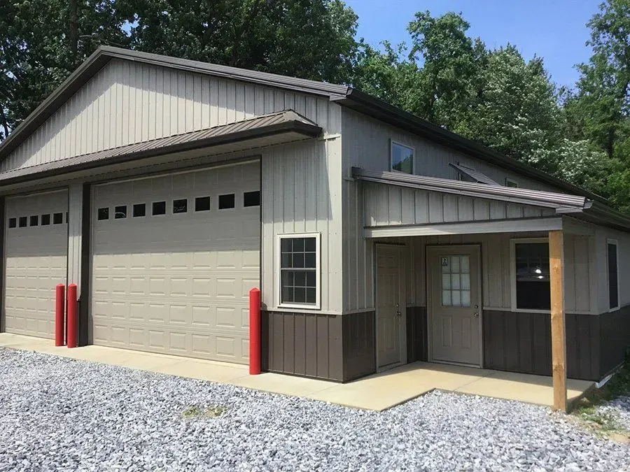 Tan and brown metal building with garage doors and entry.