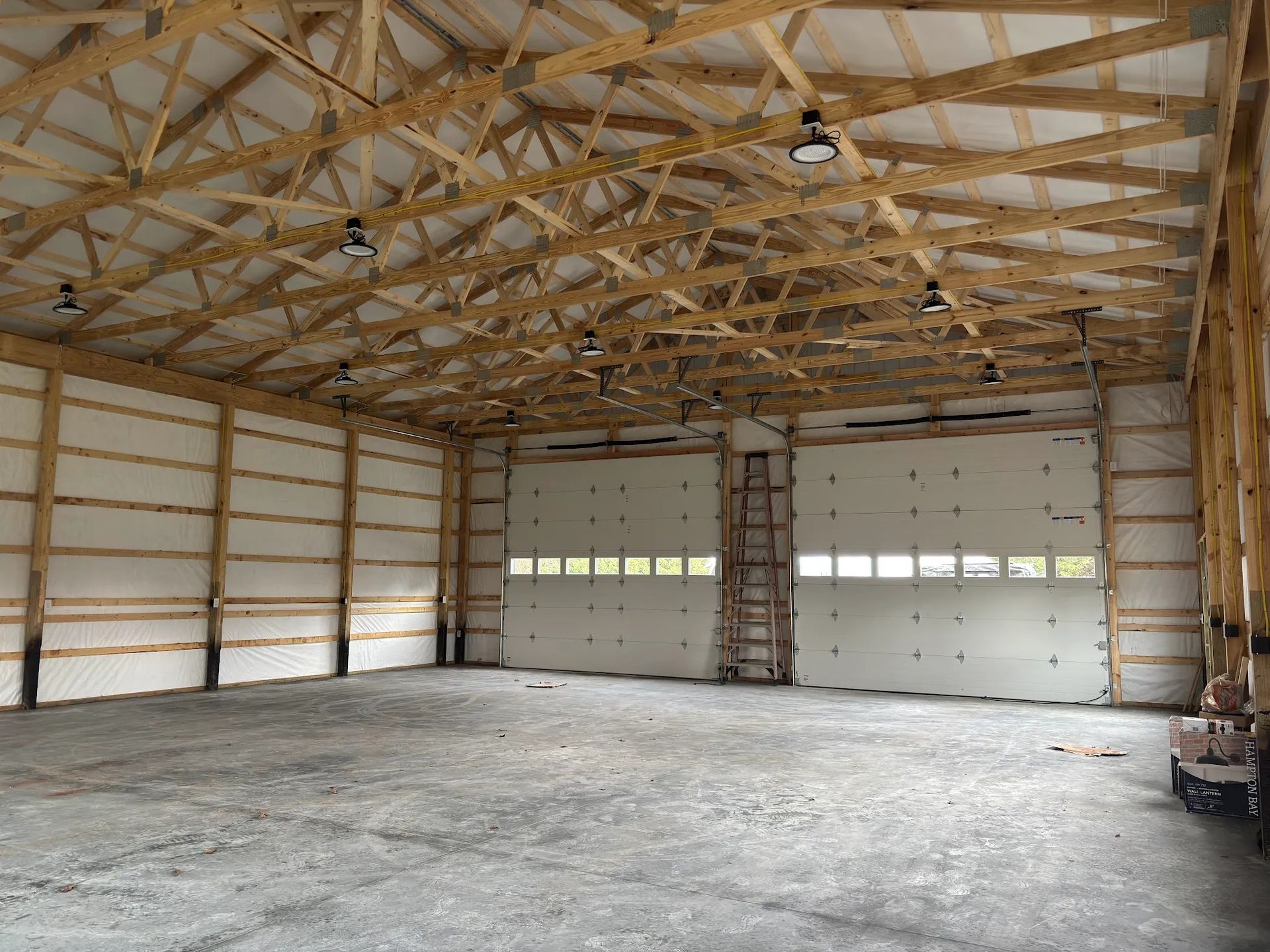 Interior of a large empty building with a wooden frame and closed garage doors.
