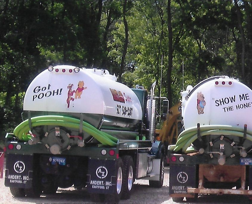 Two colorful promotional tanks on trailers in a wooded area, one reading “Go! POOH!” and the other “SHOW ME THE MONEY!”