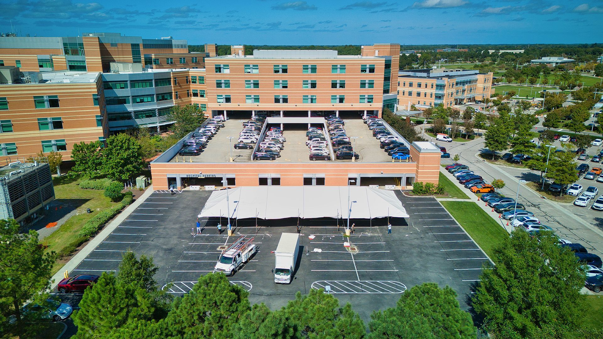 Aerial view of a hospital with a rooftop parking lot and outdoor parking below
