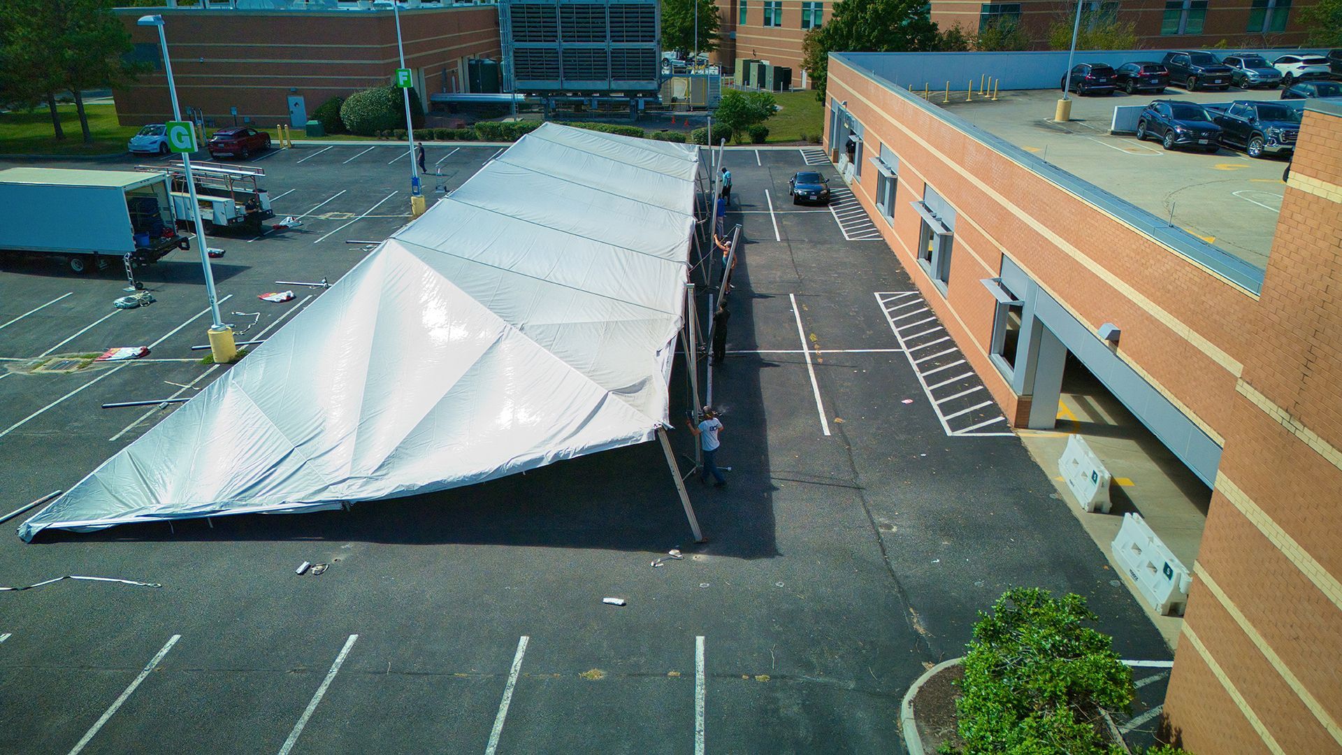 Tent installation in a parking lot next to a brick building