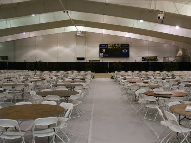 A large room with tables and chairs and a scoreboard