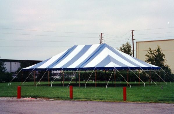 A blue and white striped tent is sitting in a grassy field