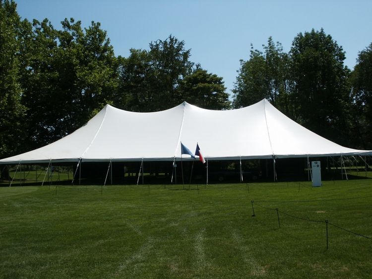 A large white tent is in the middle of a grassy field
