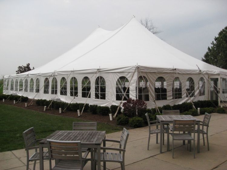 A large white tent with tables and chairs underneath it