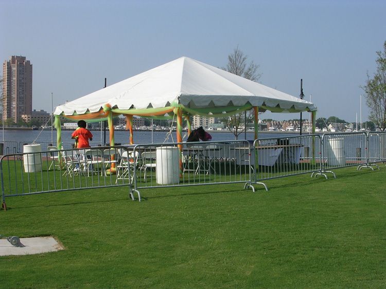 A man in an orange shirt is standing under a white tent