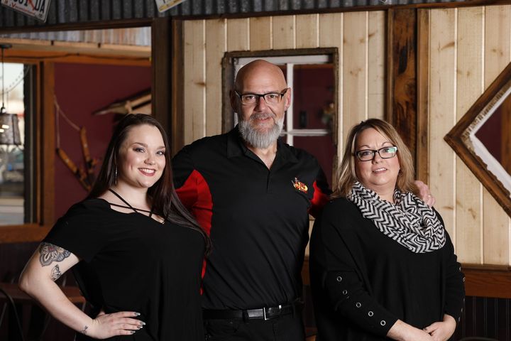 A man and two women are posing for a picture in a restaurant.