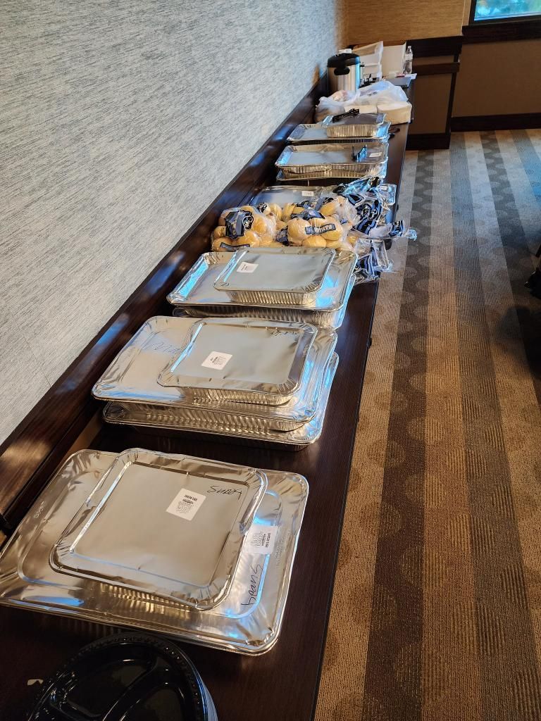 A row of aluminum foil containers sitting on top of a wooden table.