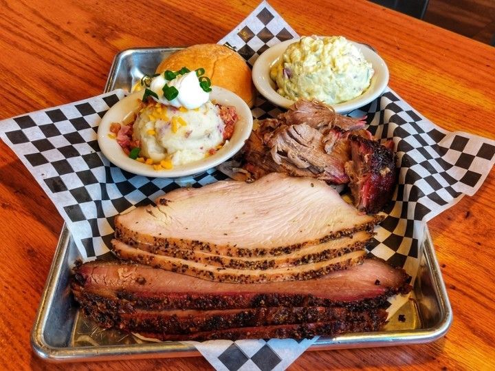 A tray of meat and potatoes on a wooden table.