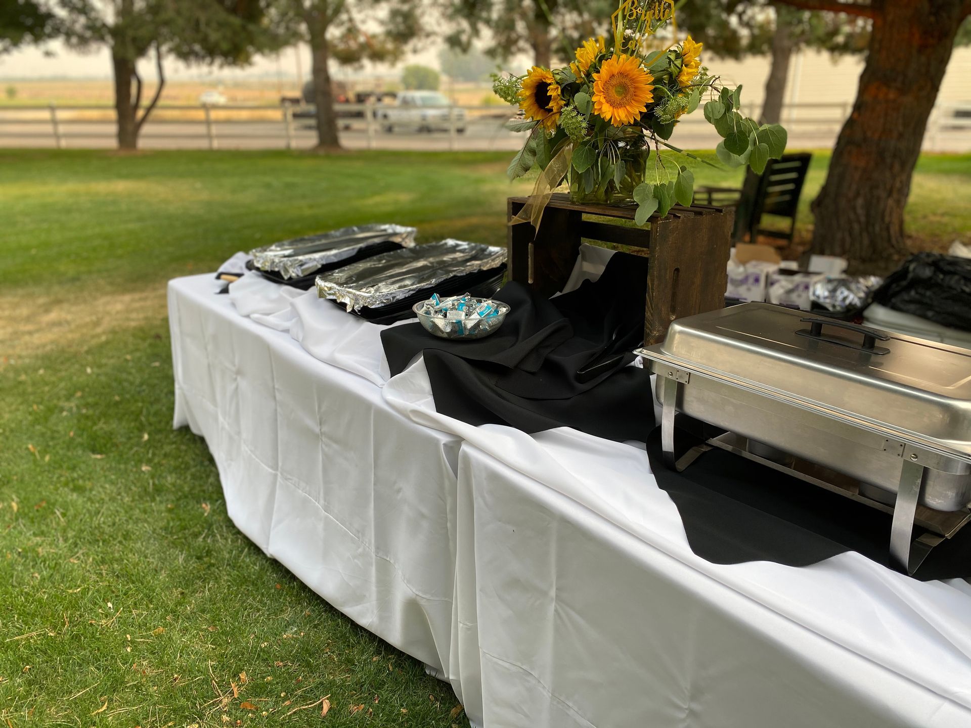 A long table with a bunch of food on it in a park.