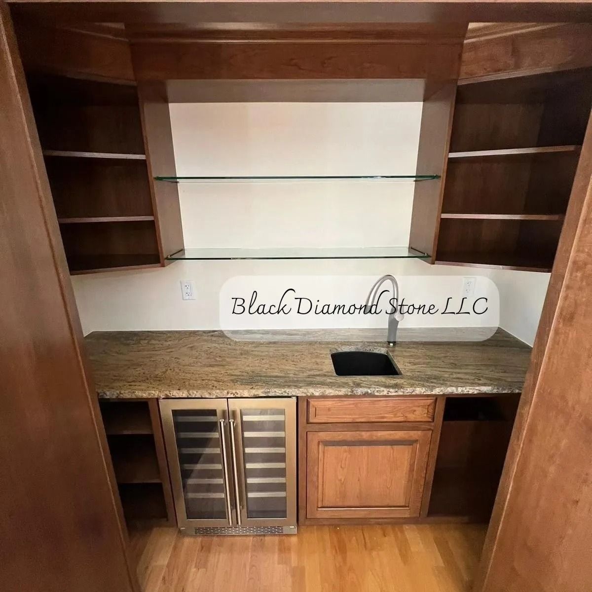Built-in bar with granite countertop, sink, wine cooler, and shelves; wooden cabinetry.