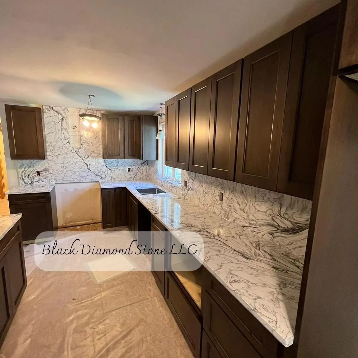 A kitchen with dark wood cabinets and white marble countertops. Unfinished construction evident.