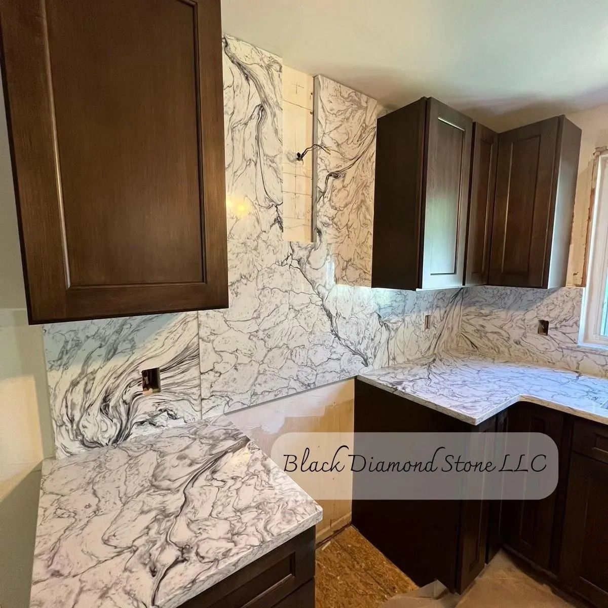 Kitchen remodel with dark cabinets, white marble countertops, and backsplash.