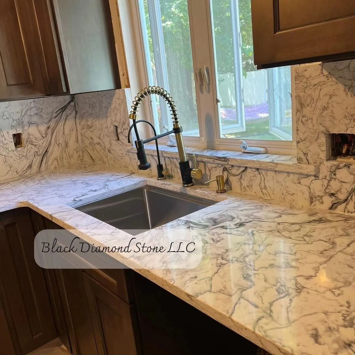 Kitchen with white marble countertops, dark cabinets, and a window above the sink.