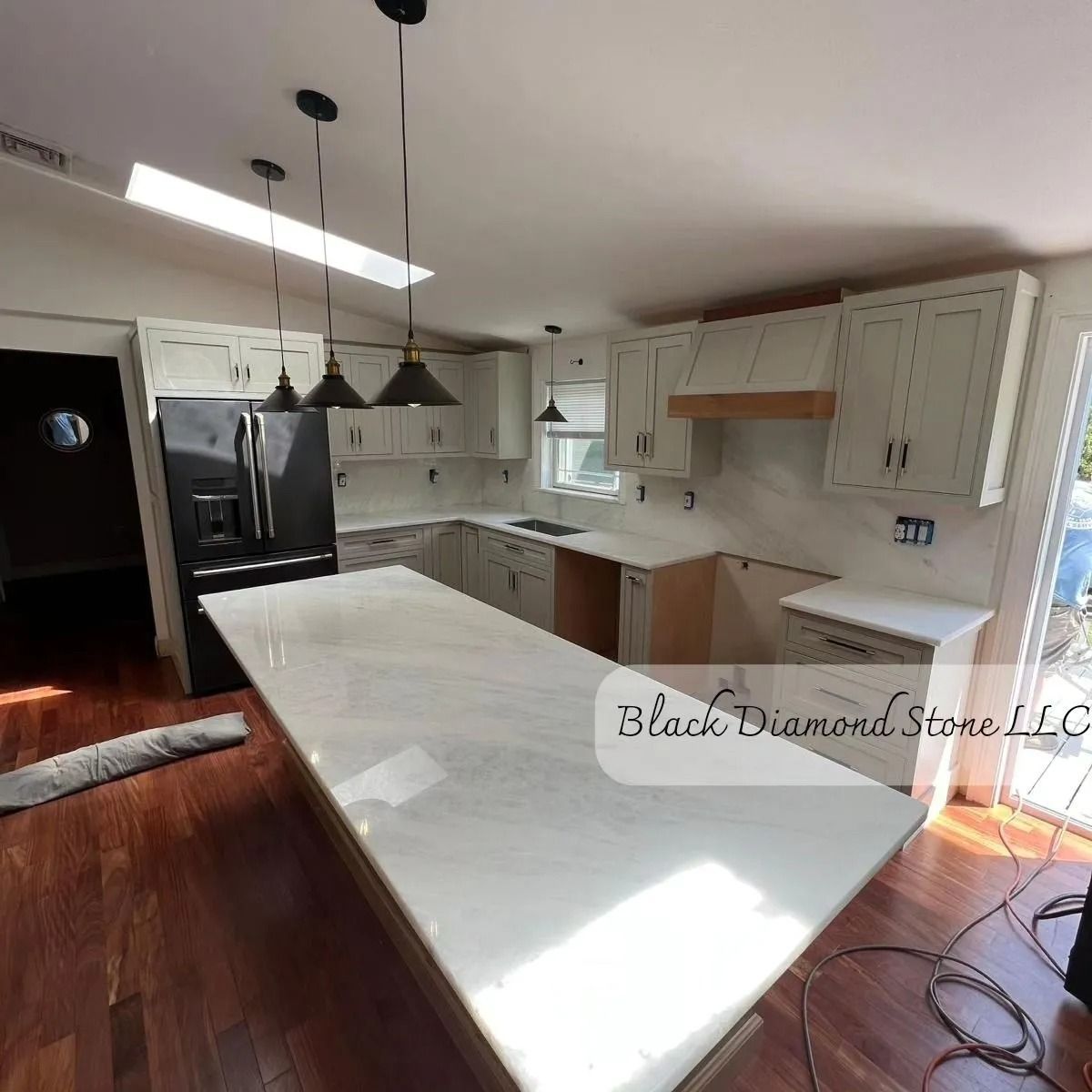 A newly remodeled kitchen with white cabinets, marble countertops, and a large island.