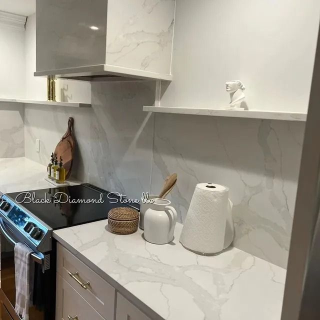 White marble kitchen countertop with a stove, shelves, and various decorative items.