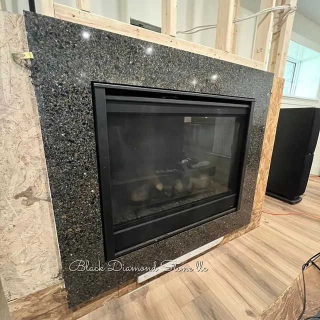 Granite fireplace surround with black firebox. Construction in progress, wood framing visible.