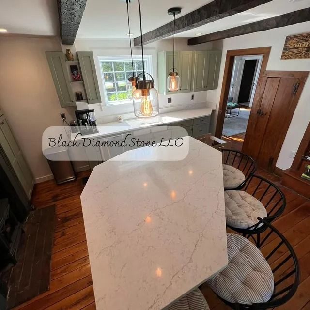 Kitchen with white countertops, green cabinets, and wooden beams. Island with chairs.