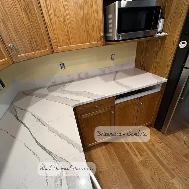 Kitchen with oak cabinets and white marble countertops. A microwave is mounted above a cabinet.