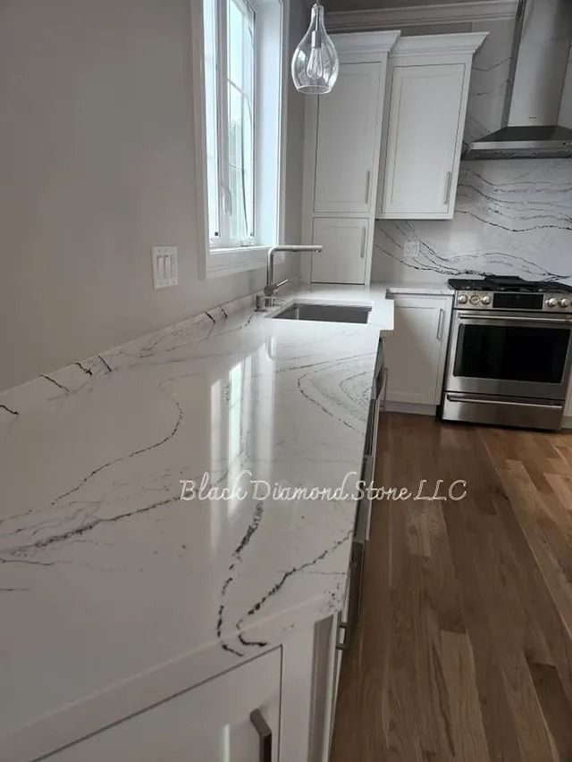 White kitchen countertop with dark veining, sink, and stainless steel oven.
