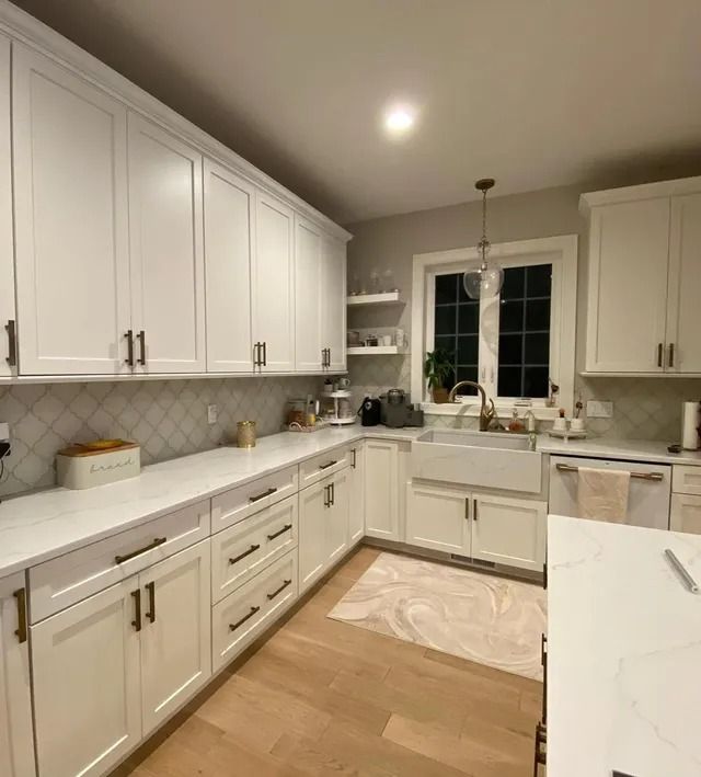 White kitchen with cabinets, countertops, and a farmhouse sink, hardwood floor.