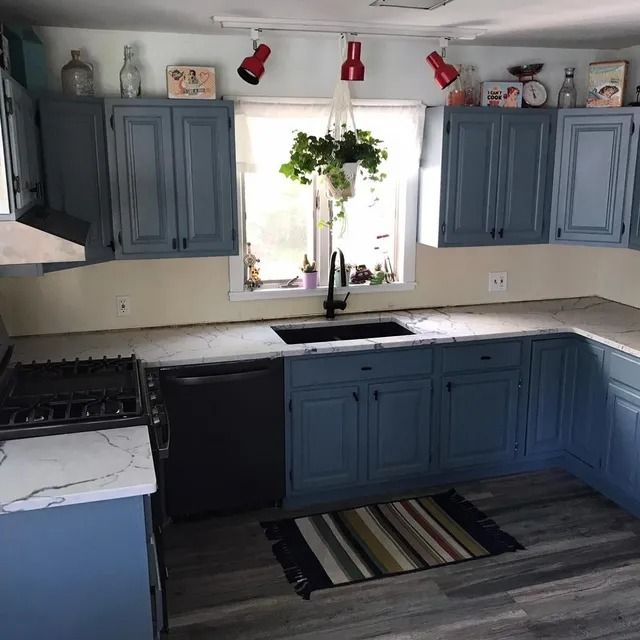 Blue kitchen cabinets with white countertops, a sink, and a rug.